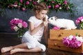 Little girl playing with real rabbit. Child and white bunny on Easter on flower background. Toddler kid feeding pet animal. Kids Royalty Free Stock Photo