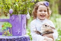 Little girl  playing with real rabbit in the garden. Laughing child at Easter egg hunt with  pet bunny. Spring outdoor fun for Royalty Free Stock Photo