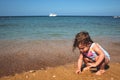 Little girl playing on a sandy beach by the sea Royalty Free Stock Photo