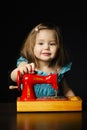 Little girl is playing with sewing machine Royalty Free Stock Photo