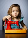 Little girl is playing with sewing machine Royalty Free Stock Photo