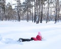 Little girl playing in snowdrift and having fun with fresh snow in park. Active outdoors leisure for kids on nature in snowy Royalty Free Stock Photo