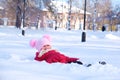 Little girl playing in snowdrift and having fun with fresh snow in park. Active outdoors leisure for kids on nature in snowy Royalty Free Stock Photo