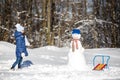 Little girl playing with a snowman Royalty Free Stock Photo