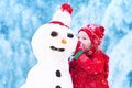 Little girl playing with a snowman Royalty Free Stock Photo