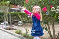 Little beautiful girl walks with a soft toy in their hands. On open air.Little girl playing with soap bubbles in the garden Royalty Free Stock Photo