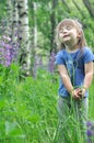 Little girl playing in sunny blooming forest. Toddler child picking lupine flowers. Kids play outdoors. Summer fun for family with Royalty Free Stock Photo