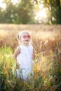 Little girl playing in sunny summer field. Baby in white dress and sunglasses