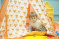 Little girl playing in a tent with red fox print. Toddler playing hide and seek in a toy house. Light and bright playroom.