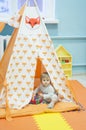 Little girl playing in a tent with red fox print. Toddler playing hide and seek in a toy house. Light and bright playroom.