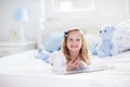 Little girl playing with toy and reading a book in bed Royalty Free Stock Photo