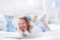 Little girl playing with toy and reading a book in bed Royalty Free Stock Photo