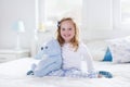 Little girl playing with toy and reading a book in bed Royalty Free Stock Photo