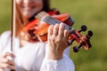 little girl is playing violin outdoor with garden in the background on sunny summer day. Image with selective focus and Royalty Free Stock Photo