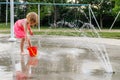 Little girl playing at water splash pad fountain in the park playground during hot summer day Royalty Free Stock Photo