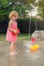 Little girl playing at water splash pad fountain in the park playground on a hot summer day. Royalty Free Stock Photo