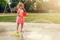 Little girl playing at water splash pad fountain in the park playground on a sunny summer day Royalty Free Stock Photo