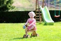 Little girl playing with wheel horse in the garden