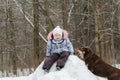 Little girl playing in winter forest on snowy hill