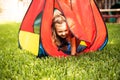 Little girl playing in the yard in a colorful tent, Child having fun playing house.