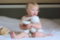 Little girl plays in bed with teddy bear Royalty Free Stock Photo