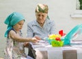 A little girl plays a board game with an older woman in a village in the yard. Have fun having fun together. Family relationship