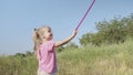 Little girl plays with butterfly net of tall grass in city park. Cute little girl is playing with aerial insect net in meadow on Royalty Free Stock Photo