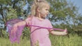 Little girl plays with butterfly net of tall grass in city park. Cute little girl is playing with aerial insect net in meadow on Royalty Free Stock Photo