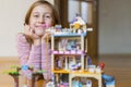 Little girl plays with a children`s constructor at home. Little girl playing with lots of colorful plastic blocks constructor and Royalty Free Stock Photo