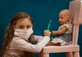 Little girl plays doctor, makes an injection to the doll Royalty Free Stock Photo