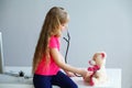 Little girl plays in doctor toy bear and stethoscope Royalty Free Stock Photo