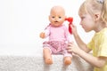 A little girl plays with a doll examines her ears. The concept of pediatric otolaryngology in medicine, treatment of otitis media Royalty Free Stock Photo