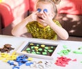 Little girl plays with geometric mosaic details and has fun and dabbles. game for creativity. Leisure of child, development of