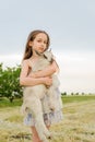 Little girl plays and huhs goatling in country, spring or summer nature outdoor. Cute kid with baby animal, countryside, forest,