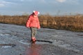 Little girl plays in puddle, children`s fun, unforgettable moments, dirty and wet shoes, fun with father, life in village, sunlig Royalty Free Stock Photo