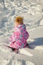 A little girl plays in the snow with snowballs in winter. Happy childhood. a child in a winter jacket.