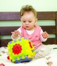 Little girl plays a toy baby on the bed Royalty Free Stock Photo