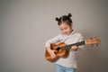 Little girl plays ukulele. Creative development in children. Musical education from childhood. Teaching music online at home