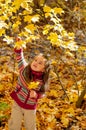 Little girl plucks leaves in autumn park