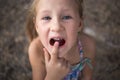 Little girl points the finger at a wobbly baby tooth