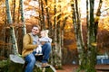 Little girl points her dad into the distance while sitting on his knees on a stump in an autumn park Royalty Free Stock Photo