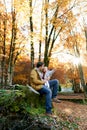 Little girl points to a tree while sitting on her dad knees on a stump in an autumn park Royalty Free Stock Photo