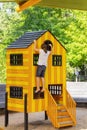 Little girl with pony tail and sandy feet climbs playhouse on playground in the Gathering Place public park in Tulsa OK Royalty Free Stock Photo