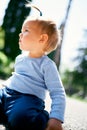 Little girl with a ponytail sits on her knees on the road. Close-up