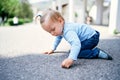 Little girl with a ponytail sits on her knees on the road in the park Royalty Free Stock Photo