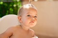 Little girl with a ponytail sits peeping at someone. Portrait