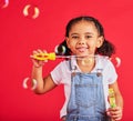 Little girl, portrait or bubbles playing on isolated red background in hand eye coordination, kids activity or fun game Royalty Free Stock Photo