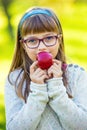 Little girl portrait eating red apple in garden. Royalty Free Stock Photo