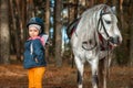 Little girl portrait, stands next to a white pony close-up on the background of nature. Jockey, epodrome, horseback riding Royalty Free Stock Photo