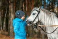 Little girl portrait, stands next to a white pony close-up on the background of nature. Jockey, epodrome, horseback riding Royalty Free Stock Photo